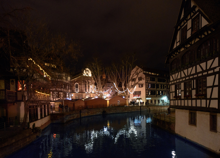 STRASBOURG, FRANCE - DEC 6, 2016: Christmas market in Place Benjamin Zix with its reflection in the Ill river at dusk with Christmas stalls and people shopping drinking mulled wineのeditorial素材