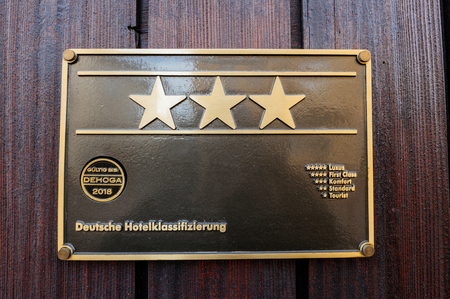 Hotel star rankings on three star German hotel facade - five star for luxury, four stars for first class, three stars for comfort, two stars for standart and one star for tourist deutsche hotelklassificazierungの写真素材