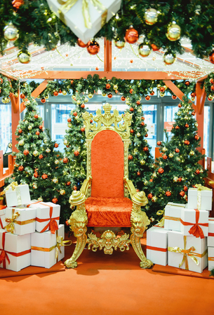 Luxurious red chair Santa Claus throne surrounded by multiple gift boxesの写真素材