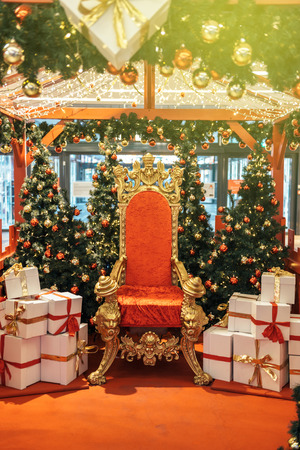Majestic and luxurious red and gold chair Santa Claus throne surrounded by multiple presents white boxes with red ribbon gift boxes vintage modernの写真素材