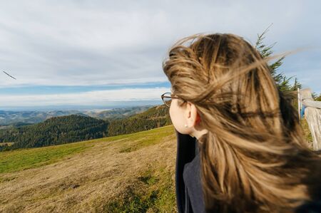 Young beautiful woman wearing glasses contemplating mountains and model plane, the hills looking toward new experiences, love, job, dream house, children and bright futureの写真素材