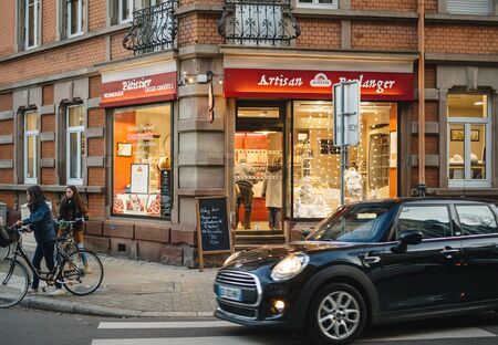 STRASBOURG, FRANCE - DEC 01, 2016: Banette Artisan Boulanger bakery in French city with customers and Mini Cooper car driving nearbyのeditorial素材
