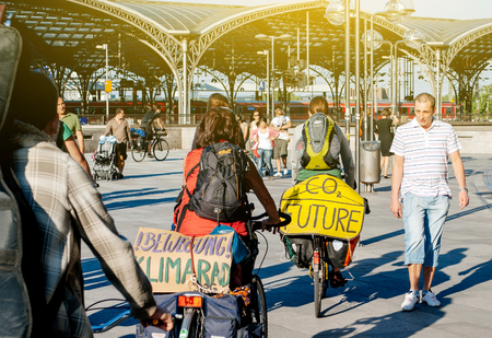COLOGNE, GERMANY - JUNE 3, 2010: Environmental friendly - Two cyclists militation against the CO2 producing and climate change passing through tourists and visitors of Cologne in the  Domplatte square in front of the Kner Domのeditorial素材