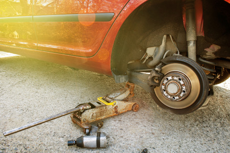Changing wheel on a red car with pressure screwdriver at the home garageの写真素材