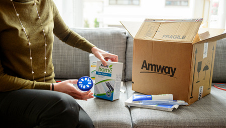 PARIS, FRANCE - OCT 20, 2015: Woman unpacking unboxing cardboard carton box with protective foam pads inside after buying ordering online via internet Multi-level marketing products from Amwayのeditorial素材