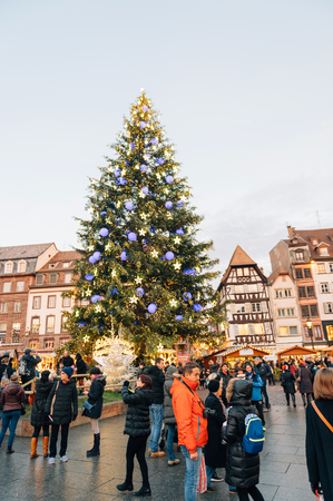 STRASBOURG, FRANCE - 9 DEC 2016: Majestic Christmas tree seen through building and people visiting the oldest Christmas Market worldwide in central Strasbourg, Alsaceのeditorial素材