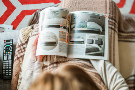 PARIS, FRANCE - AUGUST 24, 2014: View from above of woman reading IKEA Catalogue before buying bedding and bedroom furniture for her new house. The catalogue is published annually by the Swedish home furnishing retailerのeditorial素材