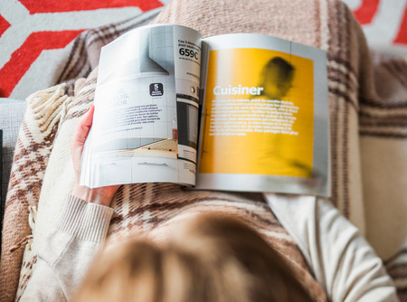 PARIS, FRANCE - AUGUST 24, 2014: View from above of woman reading IKEA Catalogue before buying kitchen furniture for her new house. The catalogue is published annually by the Swedish home furnishing retailerのeditorial素材