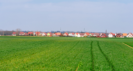 French village with beautiful houses and green agricultural fieldの写真素材