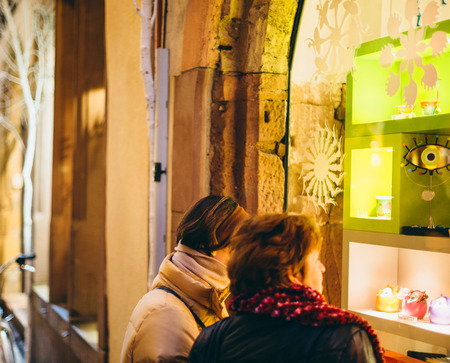STRASBOURG, FRANCE - DEC 20, 2016: Two women admiring the windows of a shop during Christmas Market with Christmas decorations and tourist in the backgroundのeditorial素材