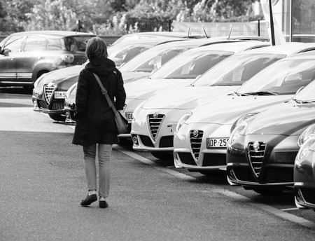 PARIS, FRANCE - OCT 10, 2015: Woman walking between rows of new car to choose the most precious one at the Alfa Romeo car store black and whiteのeditorial素材