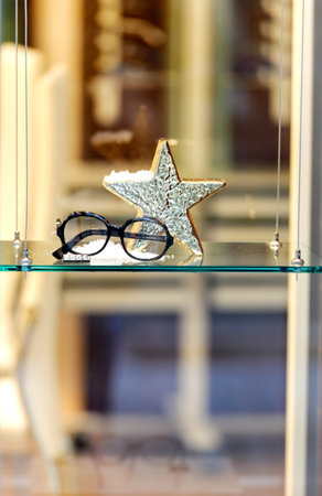 Trendy fashion sunglasses in window store with price tag and Christmas star decor covered with snow...
