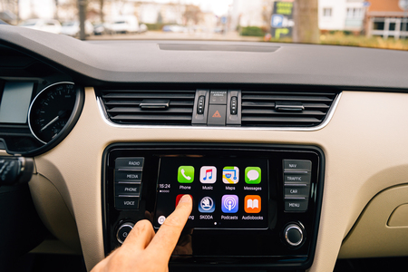 Man pressing Now Playing button on the Apple CarPlay main screen in modern car dashboard. CarPlay is an Apple standard that enables a car radio or head unit to be a display and controller for an iPhone. It is available on all iPhone 5 and later with at leのeditorial素材