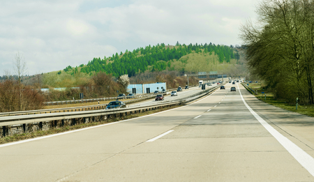 GERMANY - MAR 26, 2016: German highway - Bundesautobahn or Federal Motorway highway with busy traffic on a spring day with beautiful green fields and blue cloudsのeditorial素材