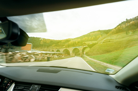 Woman driving on German village street at dusk with magnificent mountains paysage の写真素材