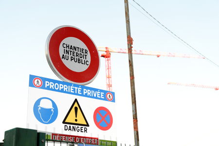 Chantier interdit au publique translated as Construction site forbidden for public from French language with cranes in the backgroundの写真素材