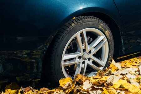 Car tire parked in autumn fall red yellow foliageの写真素材