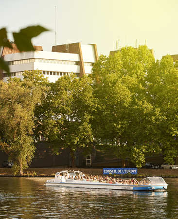STRASBOURG, FRANCE - AUG 20, 2015: Tourist Batorama boat on canal water with tourists admiring the European Parliament building on a sunny summerday with Council of Europe building and sign behind themのeditorial素材