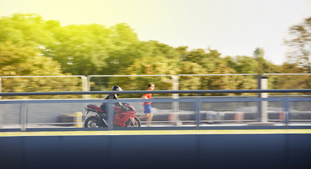 STRASBOURG, FRANCE - AUG 20, 2015 Man wearing protective clothes and helmet on a Ducatti motorcycle driving on a bridge panning focus motionのeditorial素材