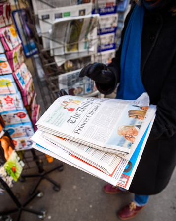 PARIS, FRANCE - JAN 21, 2017: Woman purchases a The Daily Telegraph British newspaper from a newsstand featuring headlines with Donald Trump inauguration as the 45th President of the United States in Washington, D.Cのeditorial素材