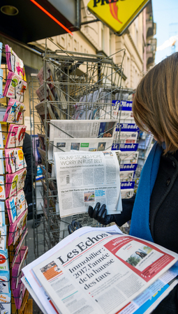 PARIS, FRANCE - JAN 21, 2017: Woman purchases a USA TODAY newspaper from a newsstand featuring headlines with Donald Trump inauguration as the 45th President of the United States in Washington, D.Cのeditorial素材