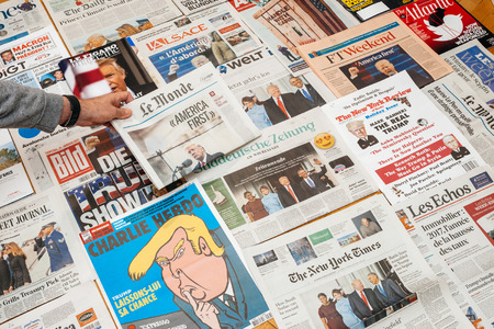 PARIS, FRANCE - JAN 21, 2017: Man holding Le Monde with America First above major international newspaper journalism featuring headlines with Donald Trump inauguration as the 45th President of the United States in Washington, D.Cのeditorial素材
