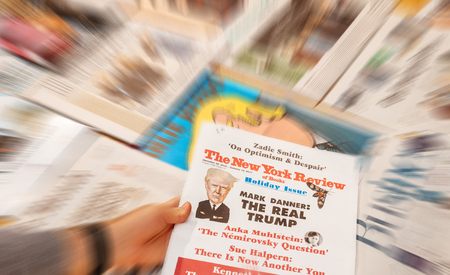 PARIS, FRANCE - JAN 21, 2017: Man holding The New york Review above major international newspaper journalism featuring headlines with Donald Trump inauguration as the 45th President of the United States in Washington, D.Cのeditorial素材