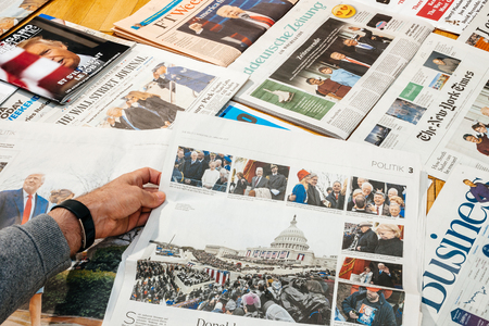 PARIS, FRANCE - JAN 21, 2017: Man holding Die Welt above major international newspaper journalism featuring headlines with Donald Trump inauguration as the 45th President of the United States in Washington, D.Cのeditorial素材