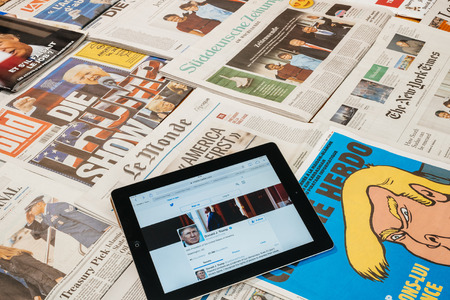 PARIS, FRANCE - JAN 21, 2017: iPad to twitter account of Donald Trump above major international newspaper journalism featuring headlines with Donald Trump inauguration as the 45th President of the United States in Washington, D.Cのeditorial素材