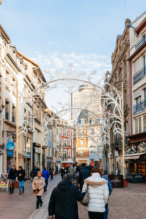 MULHOUSE, FRANCE - DEC 12, 2015: Shopping street Rue Merciere in central Mulhouse during Christmas Market with people entering shops to buy gifts and foodのeditorial素材