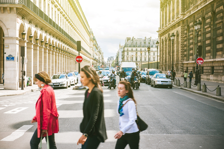 PARIS, FRANCE - AUG 18, 2014: Group of people crossing street in front of Louvre Palace in the Place de Palais Royal on a sunny summer day in PAris, France Capital with majestic Rue de Rivoli in the backgroundのeditorial素材