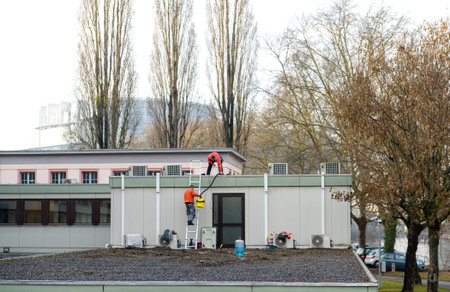 STRASBOURG, FRANCE - DEB 2, 2017: Workers repairing roof of a building with the European parliament headquarter in the backgroundのeditorial素材