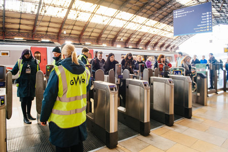 BRISTOL, UNITED KINGDOM - MAR 7, 2017: Commuters early in the morning using their oyster card and train tickets at the machine at the Bristol Temple Meads railway station with GWR Great Western Railway employee surveilling assisting the crowdのeditorial素材