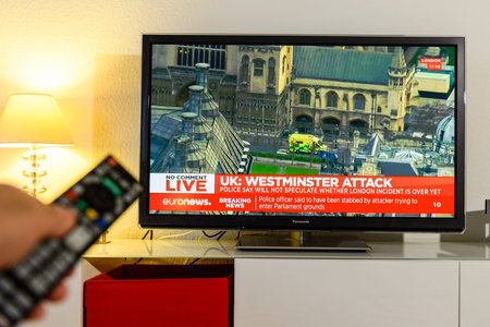 PARIS, FRANCE - MARCH 22: Man holding remote control watching BBC  channel reporting live scenes from Westminster Bridge after armed attack on March 22 in London. A police officer has been stabbed near to the British Parliamentのeditorial素材