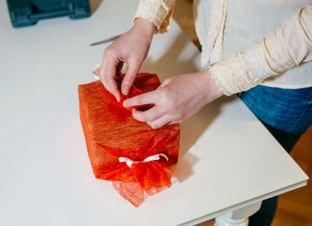 Creative woman working on her hoppby at home - wrap gift cutting red silkl - wrapping gift for the upcoming holidays and anniversaries - hand made manufacture for birthday, Christmas,の写真素材