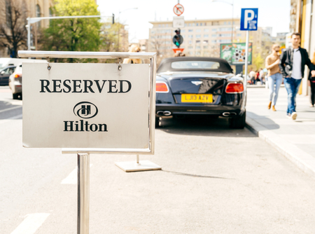 BUCHAREST, ROMANIA - APR 1, 2016: Resrved parking sign in front of the Hilton five star luxury hotel with silhouette of Bentley luxury convertible care parkedのeditorial素材