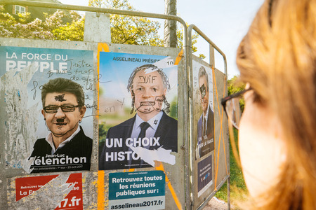STRASBOURG, FRANCE - APR 12, 2017: Woman looking at official campaign posters of Jean-Luc Melenchon,Francois Asselineau political party leaders ones of the eleven candidates running in the 2017 French presidential electionのeditorial素材
