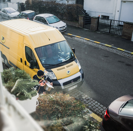 PARIS, FRANCE - APR 21, 2016: Courier exits La Poste yellow delivery van for the delivery on time package parcel - overhead viewのeditorial素材