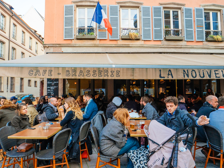 STRASBOURG, FRANCE - APR 27, 2017: Exterior of the famous authentic French La Nouvelle Poste brasserie restaurant bar in central Strasbourg with large crowd of people having fun, drinking cafe, beers, smoking outside terraceのeditorial素材
