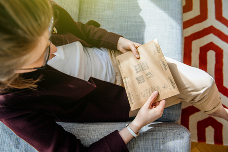 PARIS, FRANCE - APR 24 2017: View from above of woman unpacking unboxing small Amazon cardboard box with logotype printed on cardboard box side. Amazon Inc is the an American electronic e-commerce shopping companyのeditorial素材