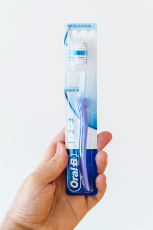 PARIS, FRANCE - FEB 26, 2017: Medium Oral-B toothbrush in male hand against white background. Oral-B is a brand of oral hygiene products, including toothbrushes, toothpastes, electric toothbrushes, mouthwashes and dental flossのeditorial素材