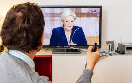 PARIS, FRANCE - MAY 03, 2017: Supporter of Marine Le Pen watch the TV debate between Emmanuel Macron and Marine Le Pen on a home TV screen on May 03, 2017 in Paris, France. France will hold the second round on May 07, 2017のeditorial素材