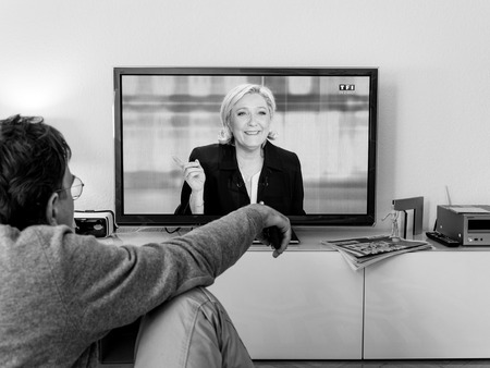 PARIS, FRANCE - MAY 03, 2017: Supporter of Marine Le Pen watch the TV debate between Emmanuel Macron and Marine Le Pen on a home TV screen on May 03, 2017 in Paris, France. France will hold the second round on May 07, 2017のeditorial素材