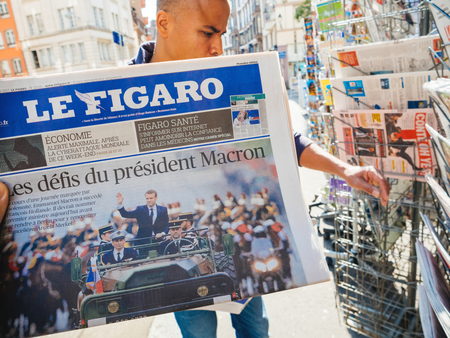 PARIS, FRANCE - MAY 15, 2017: Le Figaro newspaper with black ethnicity man buying newspaper reporting handover ceremony presidential inauguration of the newly elected French President Emmanuel Macron in Paris, Franceのeditorial素材