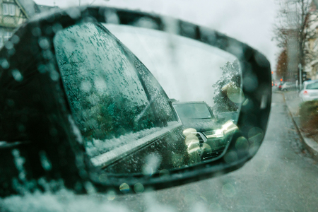 View throu car window at rear view mirror on a snowy day - senn by the driver point ov view personal perspective through wet windshield windowの写真素材