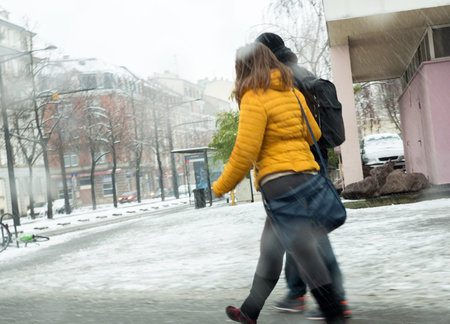 Couple silhouettes walking in city on a snowy day - defocused motion cold day