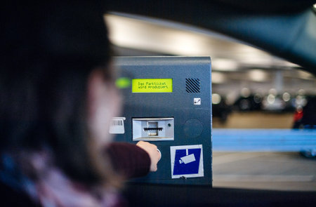 Woman waiting for the parking ticket issued by the electronic gate at the entrance of the...