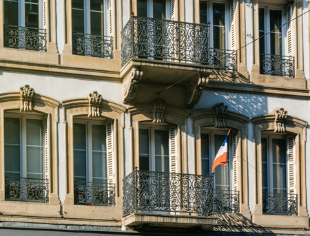 French national Flag tricolore hanged on a French balcony building on a sunny dayのeditorial素材