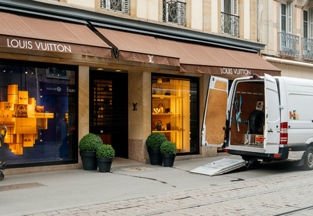 STRASBOURG, FRANCE - JUN 12, 2017: Wite delivery van suppling stock with clothes parcels and accesories a windows of the Louis Vuitton store on empthy shopping streetのeditorial素材