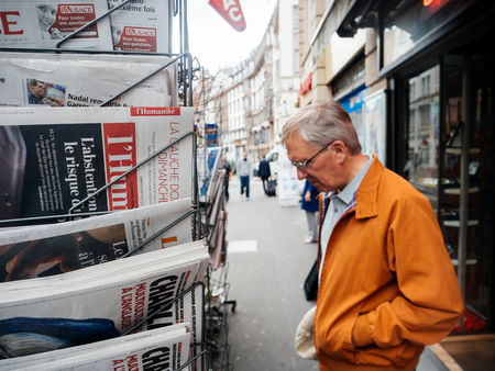 PARIS, FRANCE - JUN 12, 2017: Senior man buying at press kiosk French newspaper with reactions to French legislative election, 2017 a day after first roundのeditorial素材